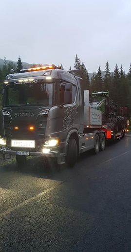 Lastebil med traktor på tilhenger